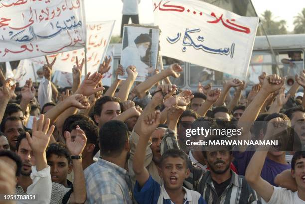 Iraqis carry portraits of assassinated Shiite cleric Mohammed Sadeq Sadr and banners expressing loyalty to his son Mogtada and rejection to...