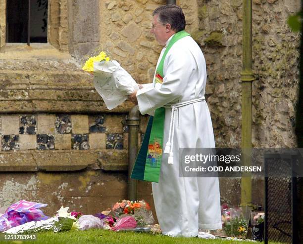 Vicar Alan Ashton of the St Andrews Church in the Cambridgeshire village of Soham lay down flowers 18 August 2002 to pay his last respect to murdered...