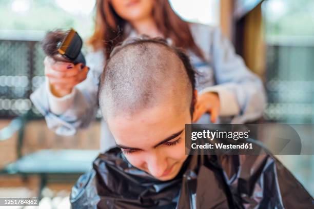 midsection of mother shaving teenage son's head with electric razor at home - shaving head stock pictures, royalty-free photos & images