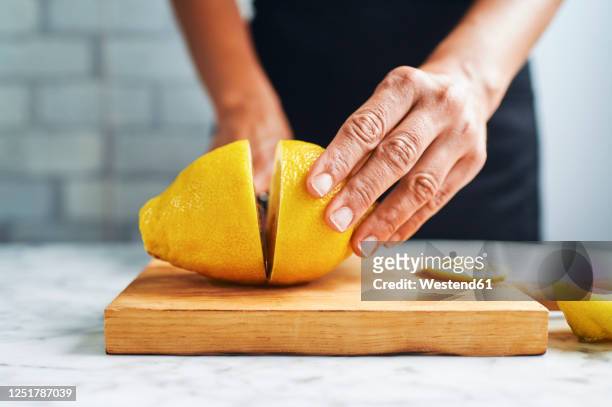 hands of woman cutting lemons on cutting board - hand cut stock pictures, royalty-free photos & images