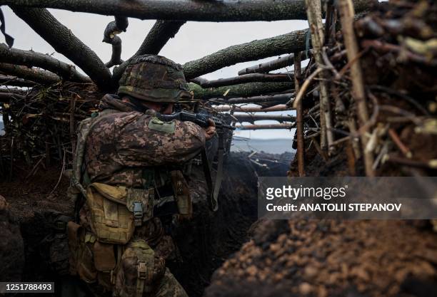 Ukrainian infantryman of the 57th Separate Motorized Infantry Brigade "Otaman Kost Khordienko" fires an assault rifle at enemy positions from a...