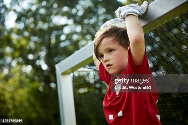 thoughtful soccer boy holding goal post at field - soccer goalkeeper stock pictures, royalty-free photos & images
