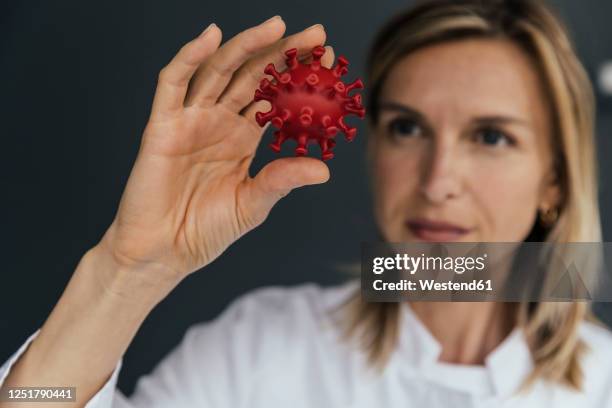 female scientist looking at 3d model of sars-cov-2 virus - human hand 3d stock pictures, royalty-free photos & images