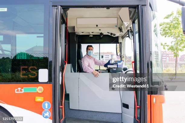 mature bus driver wearing protective mask waiting at bus station, spain - bus driver stock pictures, royalty-free photos & images