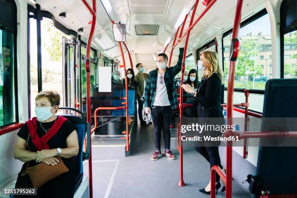 passengers wearing protective masks in public bus, spain - group of people with masks stock pictures, royalty-free photos & images