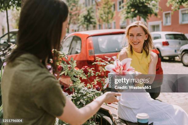 smiling woman handing over gift to friend - gift lounge stock-fotos und bilder