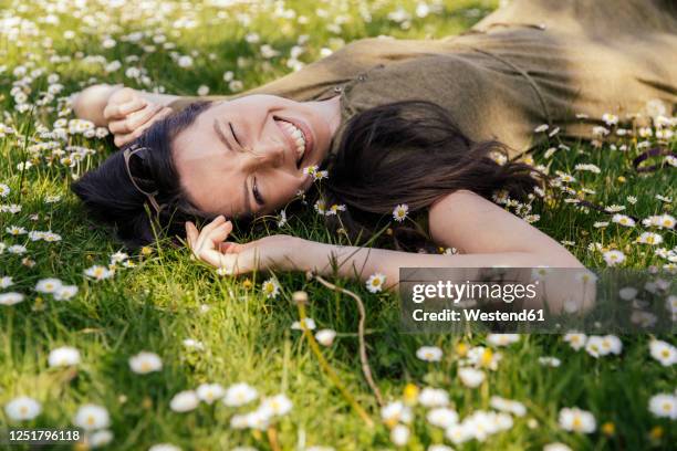 happy woman enjoying her free time while lying on grass with daisies - young woman white dress stock pictures, royalty-free photos & images