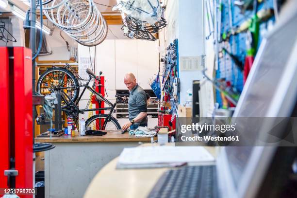 bicycle mechanic working in bike shop - sportgeschäft stock-fotos und bilder