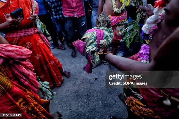 Devotee is seen holding the wrapped skull of a child during the Gajan Festival. Gajan is a Hindu festival celebrated mostly in the rural part of West...