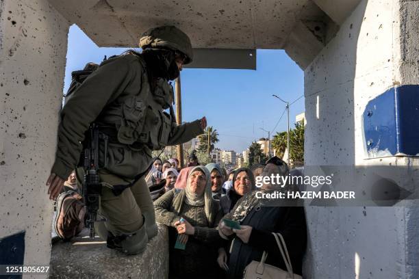 Member of the Israeli security forces directs Palestinians queueing at an Israeli checkpoint in Bethlehem in the occupied West Bank on April 14...