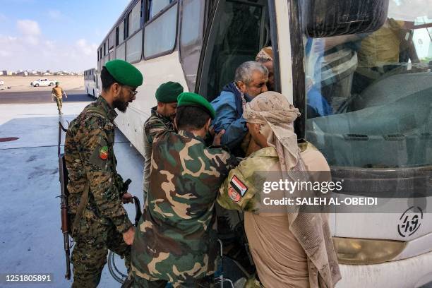 Man in a wheelchair is assisted to disembark off a bus as Yemeni Huthi rebel prisoners are released during a prisoner exchange with the...