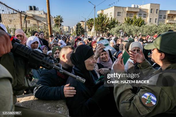 Member of the Israeli security forces directs Palestinians queueing at an Israeli checkpoint in Bethlehem in the occupied West Bank on April 14...