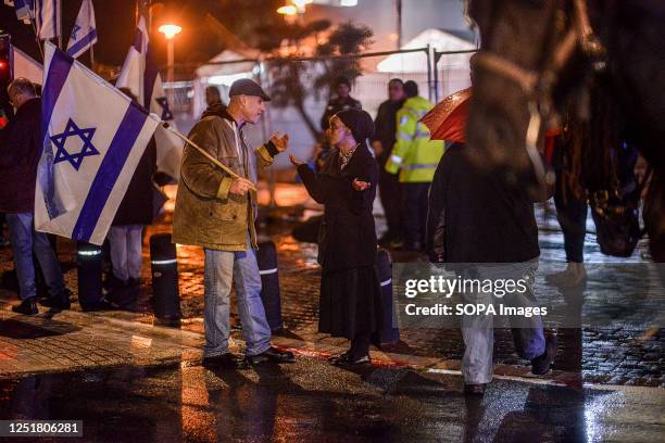 Anti reform protester holding an Israeli flag talks with a religious woman during a demonstration. Pro and Anti-judicial reform protesters...