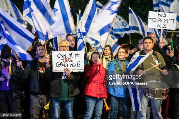 Anti-reform protestors wave the Israeli flag and hold placards that read "You have no mandate to control the court", "Be gone DyBIBIbuk" during the...