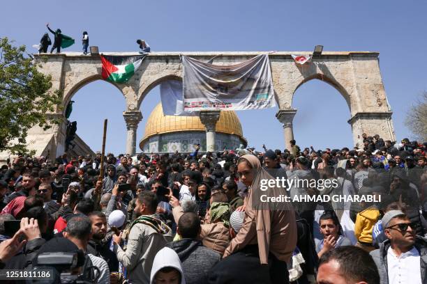 Youths hang a Palestinian national flag an a banner in front of the Dome of the Rock mosque, following the Friday noon prayers at the Al-Aqsa mosque...