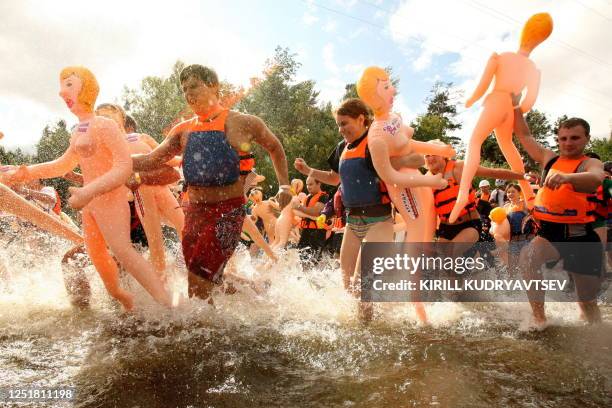 Russian men and women participate in the "Bubble Baba Challenge" blow-up sex doll swimming race on the river Vuoksa in Losevo village, some 110 kms...