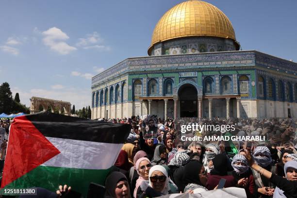 People raise a Palestinian national flag in front of the Dome of the Rock mosque, following the Friday noon prayers at the Al-Aqsa mosque compound,...