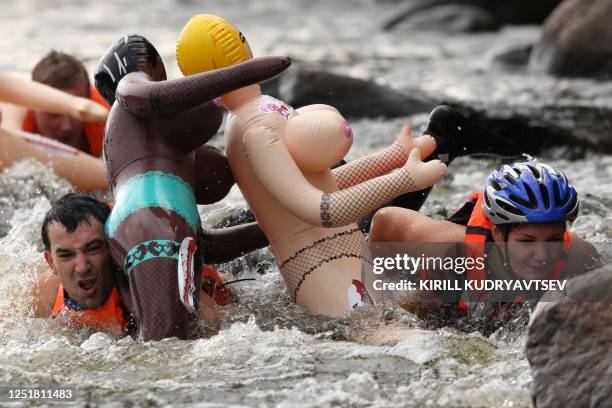 Russian men and women participate in the "Bubble Baba Challenge" blow-up sex doll swimming race on the river Vuoksa in Losevo village, some 110 kms...