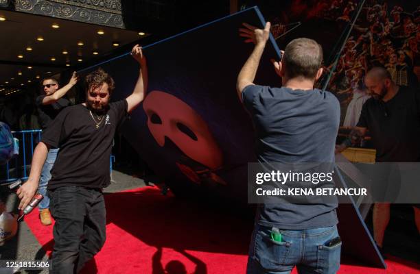 Workers removed a poster outside the Majestic Theatre in New York City on April 14, 2023. - The honor comes as Webber's iconic musical, "The Phantom...