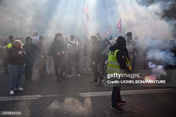 Protester holds a red flare during a demonstration after the court approved the key elements on French President's unpopular pension reform, in...