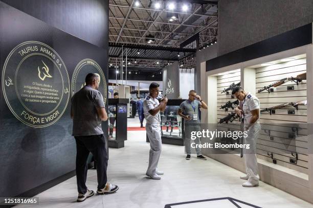 Attendees view guns displayed at the Taurus booth during the Latin American Aerospace & Defense conference and exhibition in Rio de Janeiro, Brazil,...