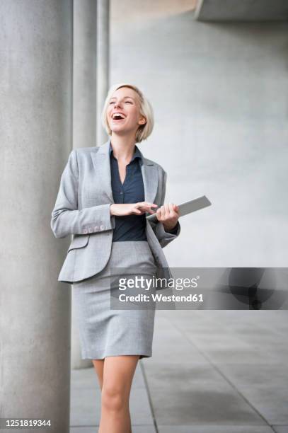 portrait of laughing blond businesswoman with tablet - geschäftskleidung stock-fotos und bilder