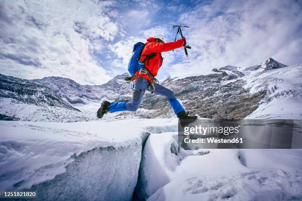 mountaineer jumping over crevasse, glacier grossvendediger, tyrol, austria - crevasse fotografías e imágenes de stock