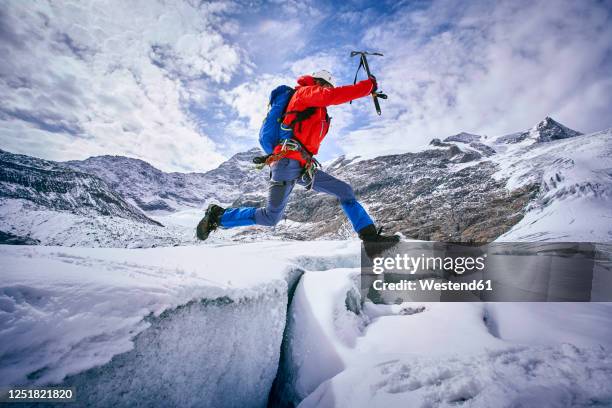 mountaineer jumping over crevasse, glacier grossvendediger, tyrol, austria - crevasse stock pictures, royalty-free photos & images