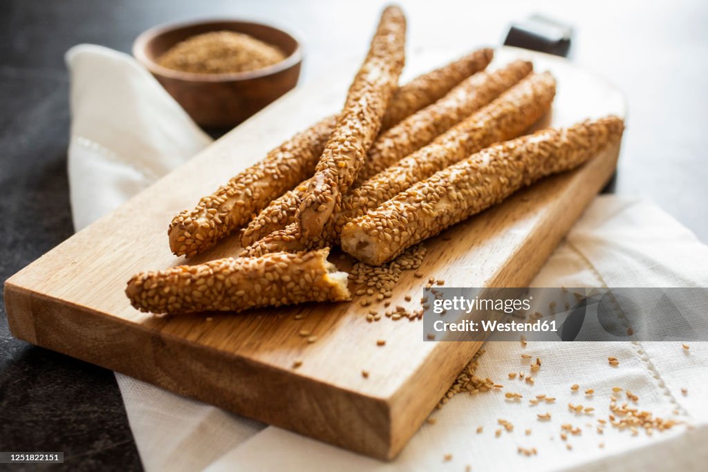 Cutting board and fresh Italian grissini breadsticks with sesame seeds