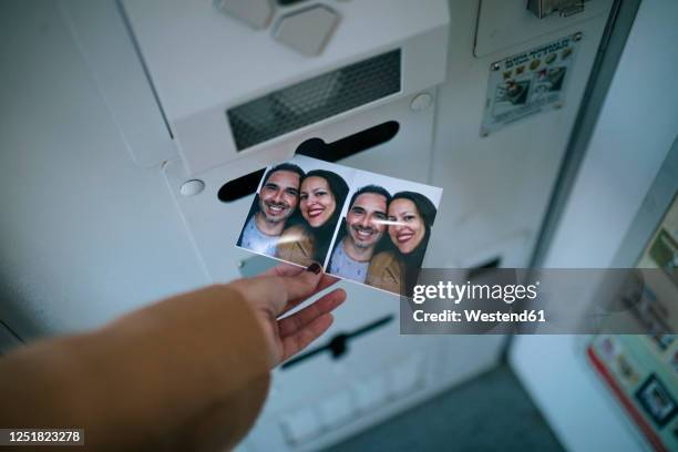 woman's hand removing photograph from photo booth - photomaton stock-fotos und bilder