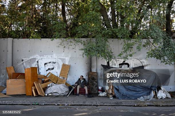 Man sits outside his makeshift house on the street in Buenos Aires on April 14, 2023. - Argentina suffers from one of the highest inflation rates in...