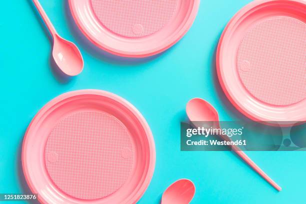 studio shot of pink empty plates and spoons against blue background - plastic cutlery stock pictures, royalty-free photos & images