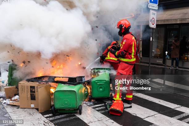 Garbage bins on fire are extinguished during a demonstration following the pension reform ruling in central Paris, France, on Friday, April 14, 2023....
