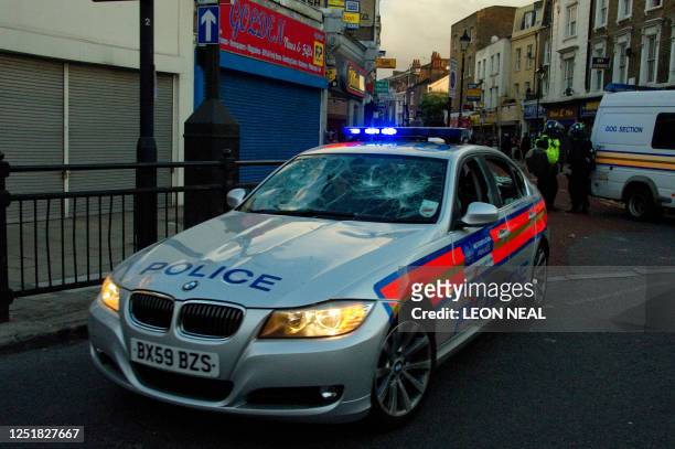 Damaged police car is driven through the police line in Hackney, north London on 8 August 2011. Now in it's third night of unrest, London has seen...