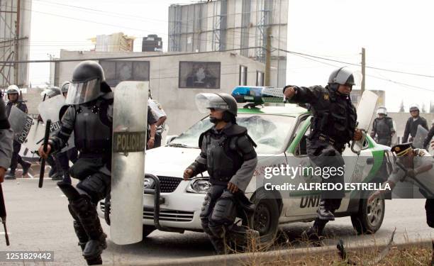 Mexican riot police spread out to stand clear of a damaged patrol car the protesters pushed towards them during clashes between police and hawkers 03...