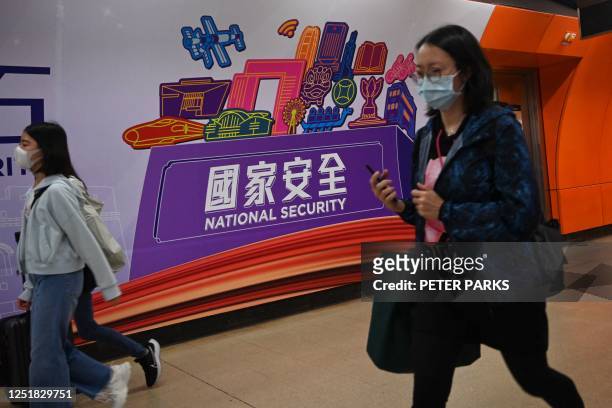 People walk past a National Security banner at a train station in Hong Kong on April 15, 2023 on National Security Education Day.