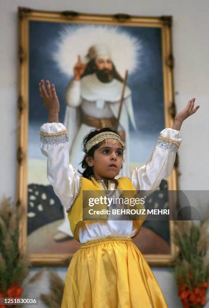 An Iranian Zoroastrian girl performs a traditional dance in front of a painting of Iranian Prophet Zarathustra during the Mehregan celebrations at...