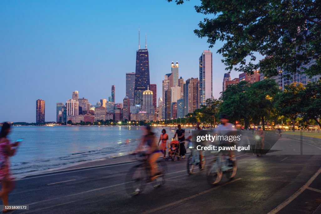 People riding bicycles at night with Chicago skyline in background