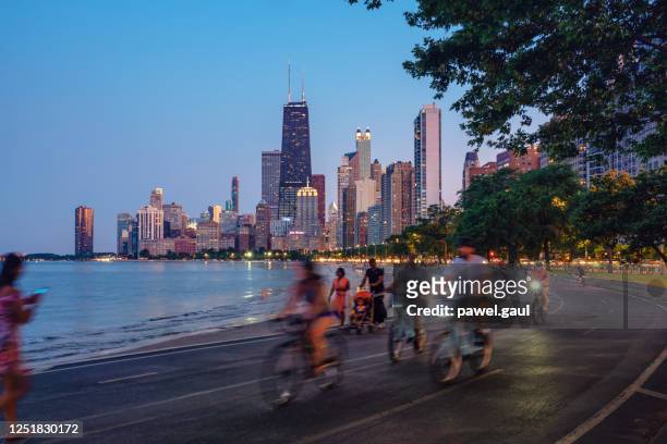 people riding bicycles at night with chicago skyline in background - michigan avenue imagens e fotografias de stock