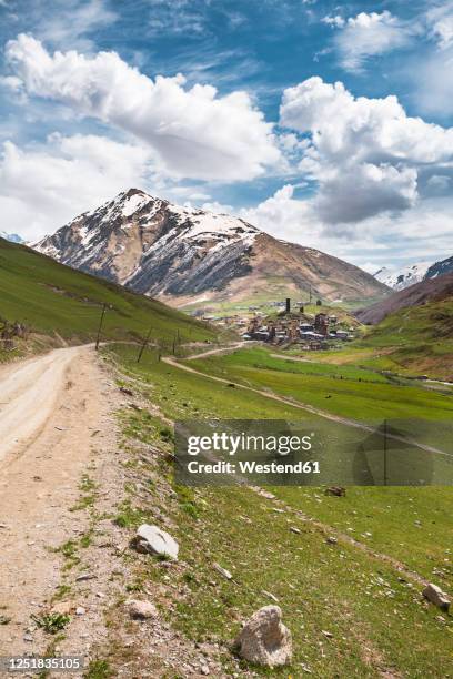 georgia, svaneti, ushguli, dirt road leading to medieval mountain village - geórgia cáucaso do sul imagens e fotografias de stock
