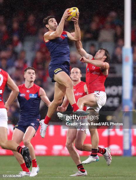 Christian Petracca of the Demons marks the ball over Andrew McGrath of the Bombers during the 2023 AFL Round 05 match between the Essendon Bombers...