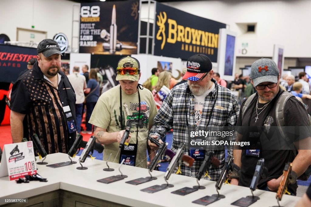 Guests check out pistols on display at the National Rifle...