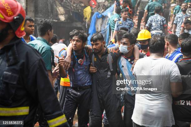 Volunteers help a sick firefighter after a horrendous fire guts shops at the clothing market in Dhaka. A massive blaze has gutted shops in Dhaka's...