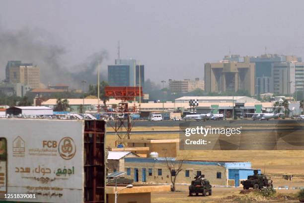 Military vehicles can be seen as smoke billows above buildings in the vicinity of the Khartoum airport on April 15 amid clashes in the city....