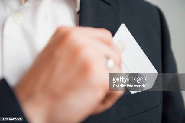 businessman removing credit card from suit pocket - businessman hands in pockets stock pictures, royalty-free photos & images