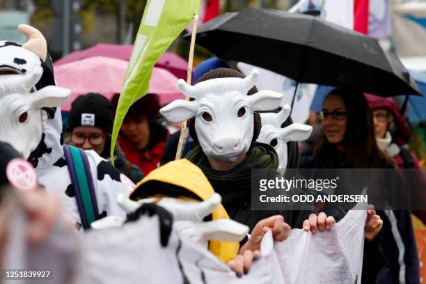 Climate activists wearing cow masks march with a banner during a demonstration of environmental movement Extinction Rebellion under the motto 'State...