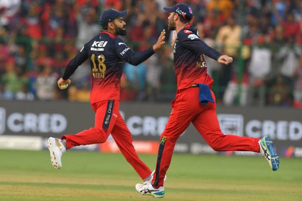 Royal Challengers Bangalore's Virat Kohli celebrates with teammate after taking the wicket of Delhi Capitals' David Warner during the Indian Premier...