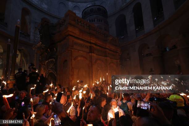 Orthodox Christians gather with lit candles around the Edicule, traditionally believed to be the burial site of Jesus Christ, during the Holy Fire...