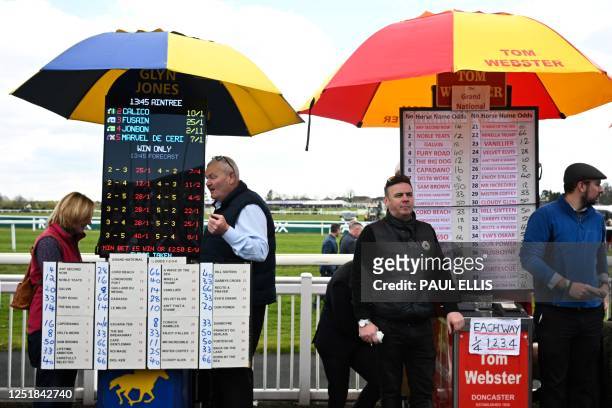 Bookmarkers wait to register the bets of racegoers during the final day of the Grand National Festival horse race meeting at Aintree Racecourse in...