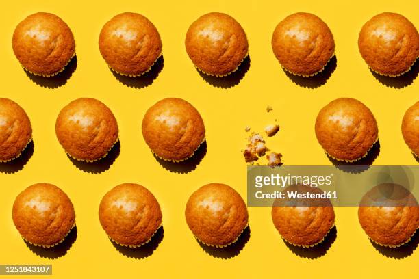 pattern of rows of muffins against yellow background with single one missing - muffin stock pictures, royalty-free photos & images
